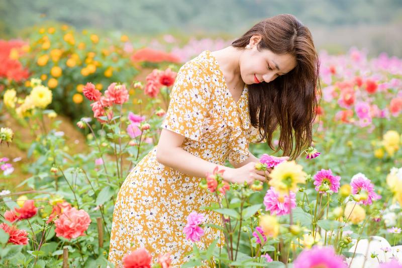 Một cô gái trẻ tên Thanh, ánh mắt trong sáng, đang mỉm cười giữa cánh đồng hoa oải hương xanh biếc, tượng trưng cho sự tinh khiết và môi trường sống trong lành.