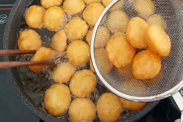 Bánh khoai tây đang được chiên vàng giòn trên chảo ngập dầu nóng