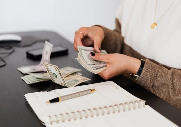 Hình ảnh tiền mặt và sổ sách, thể hiện khả năng phân tích và quản lý tài chính vượt trội của người có nốt ruồi ở tay phải