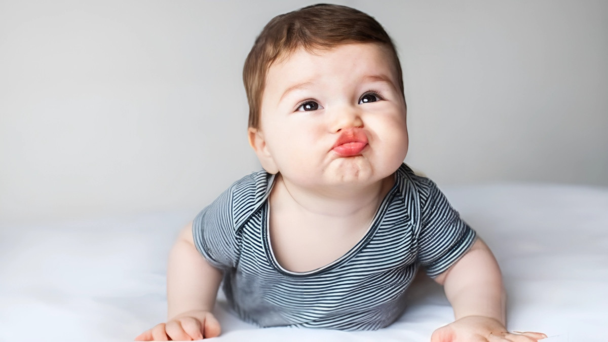 Em bé đang tạo dáng hài hước, tay đặt lên cằm
