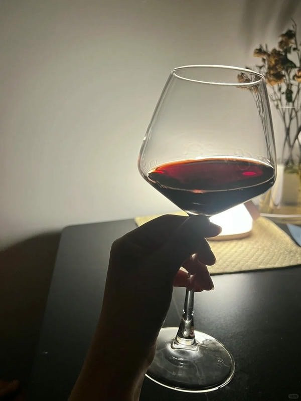 Người đàn ông cúi đầu, chai rượu trên bàn, hình ảnh nhậu một mình đầy u sầu.