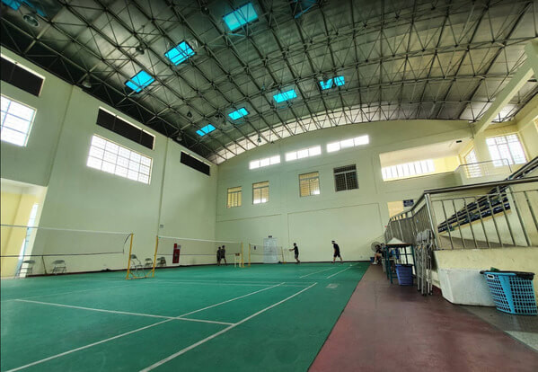 Hình ảnh một sân cầu lông hiện đại ở Hà Nội với các vận động viên đang thi đấu sôi nổi, ánh sáng tốt và không gian rộng rãi.