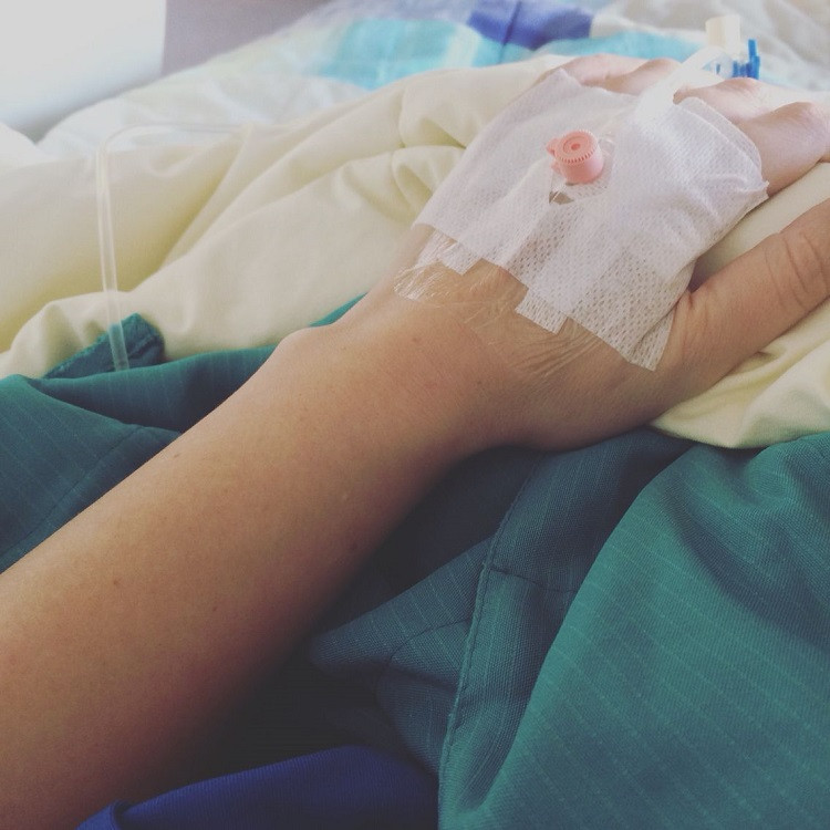 Hình ảnh chụp từ góc trên xuống bàn tay đang truyền nước biển của một bệnh nhân trong bệnh viện.