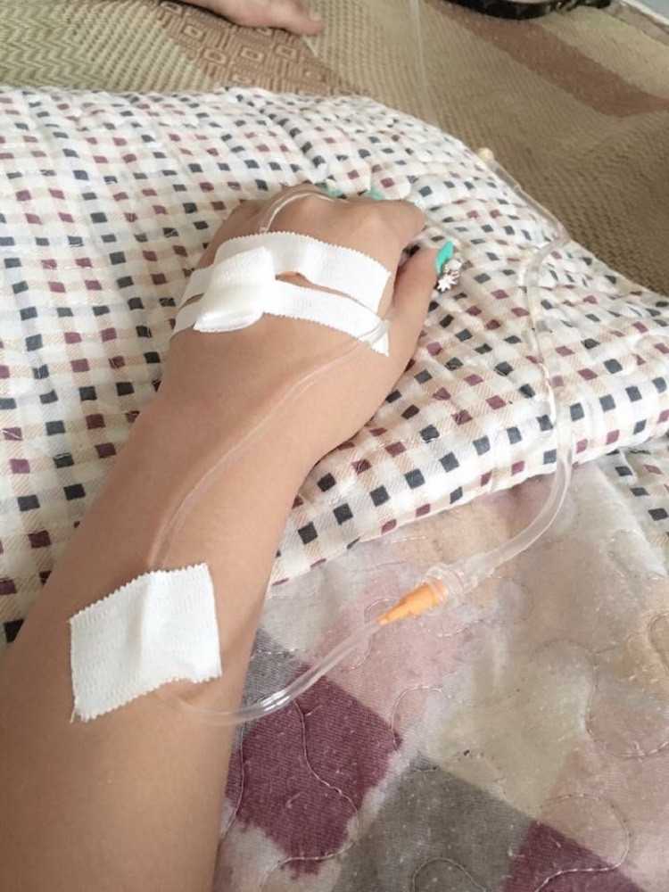 Góc nhìn từ trên xuống bàn tay và một phần cơ thể bệnh nhân đang truyền nước biển.