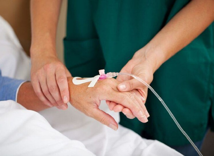 Cận cảnh tay bệnh nhân đang truyền nước biển, kim truyền dịch được cố định chắc chắn, ống dịch truyền rõ ràng.