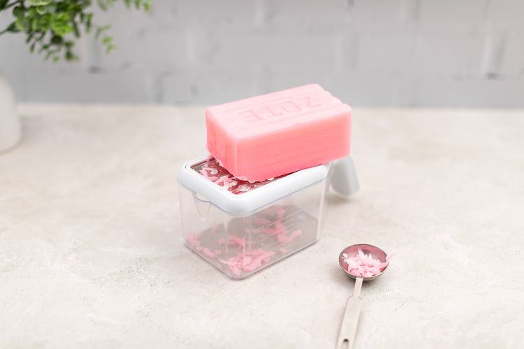 Bánh xà phòng Zote màu hồng được bào thành vảy dày bên cạnh thìa canh