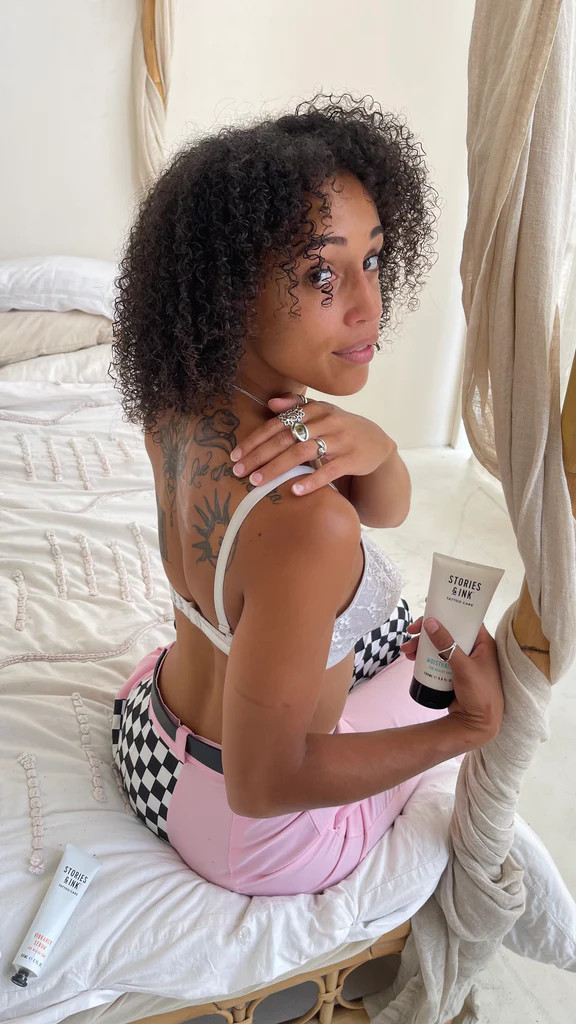 Người phụ nữ đang thoa kem dưỡng sau xăm lên hình xăm