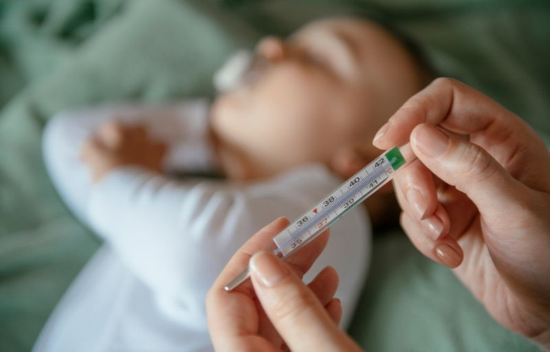 Em bé sơ sinh đang được mẹ theo dõi thân nhiệt cẩn thận