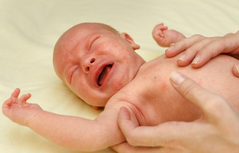 Cha mẹ đang dùng nhiệt kế đo thân nhiệt cho trẻ sơ sinh